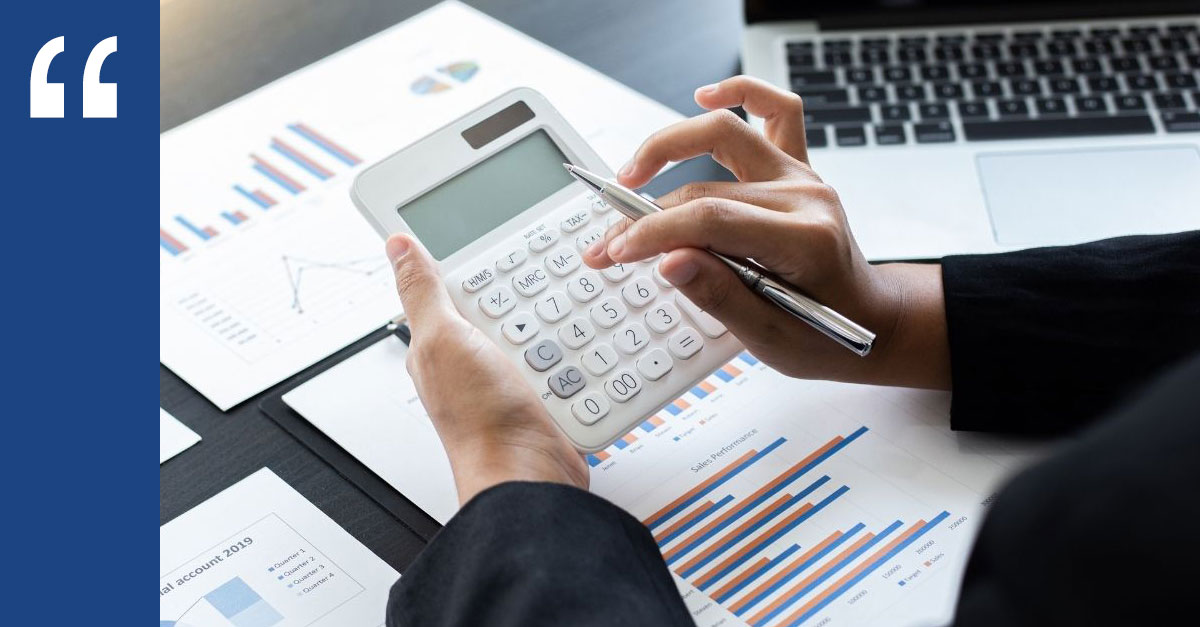 Hands using a calculator over financial charts